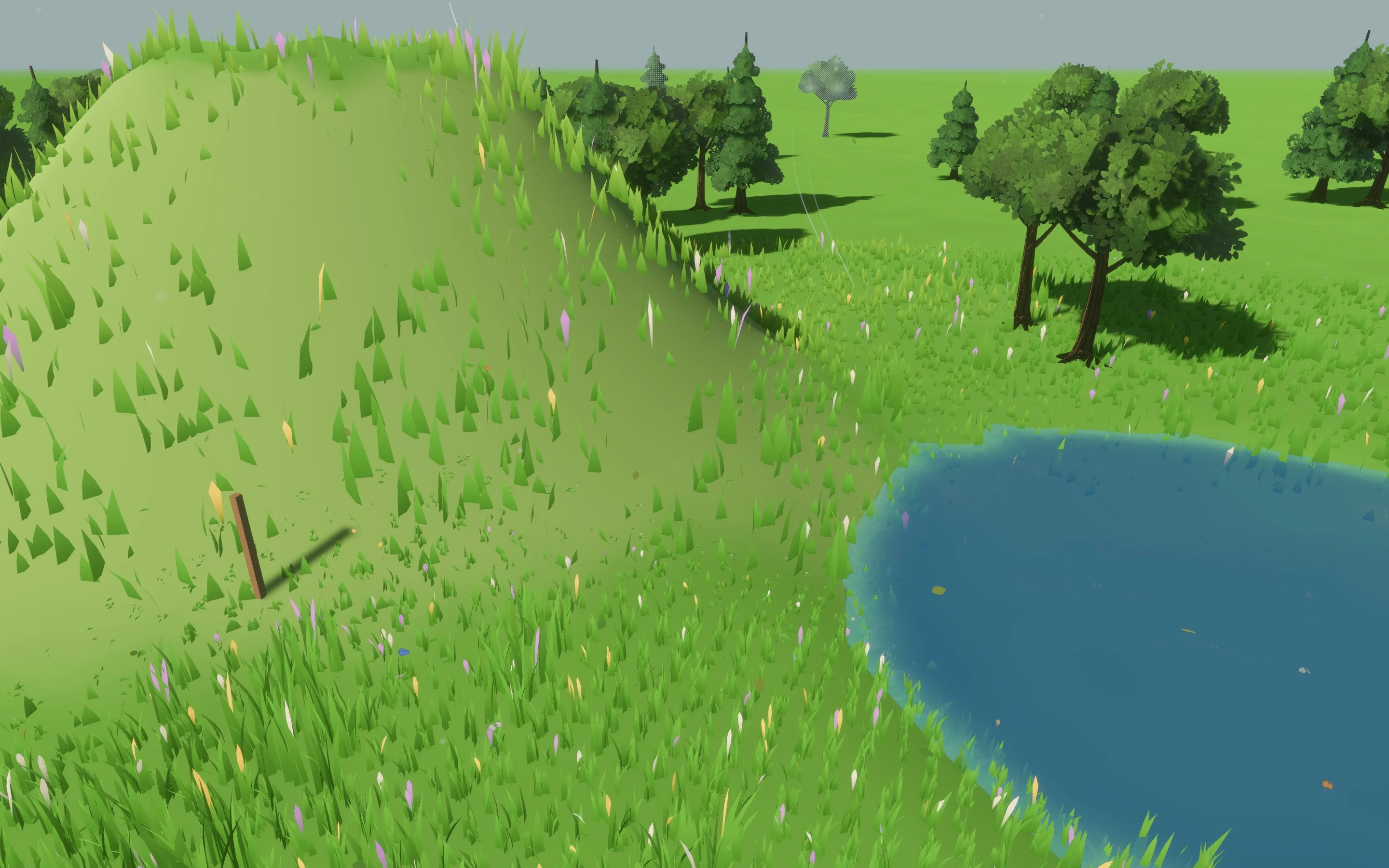 A grassy hill beside a pond in Fluid Playground, with procedural grass, flowers and trees.